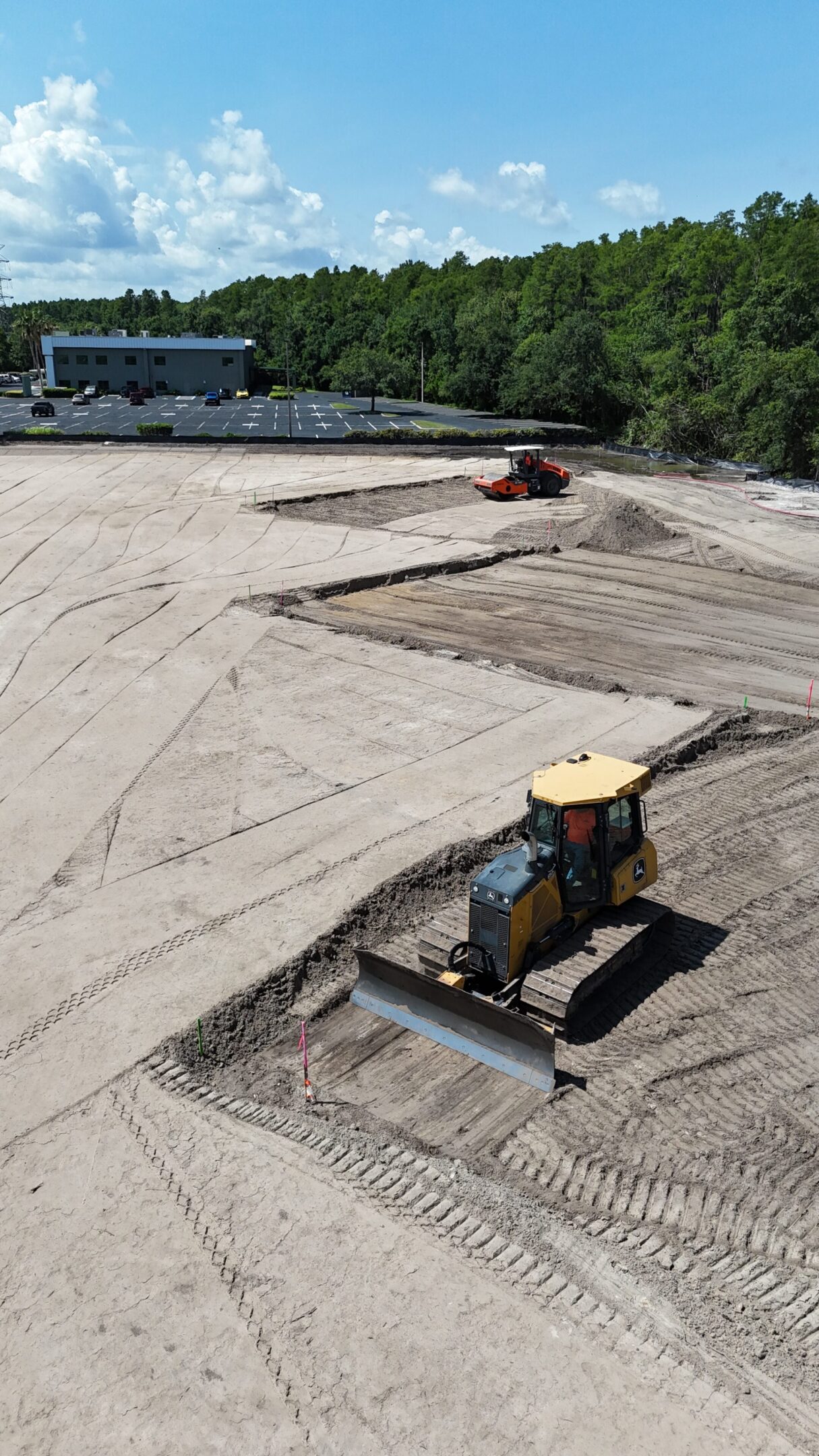 Bulldozer and excavator grading sandy construction site