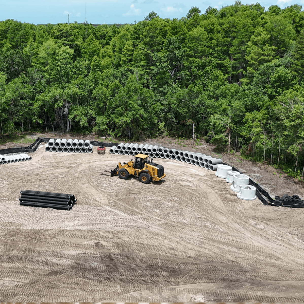 Construction site with loader and stacked concrete pipes
