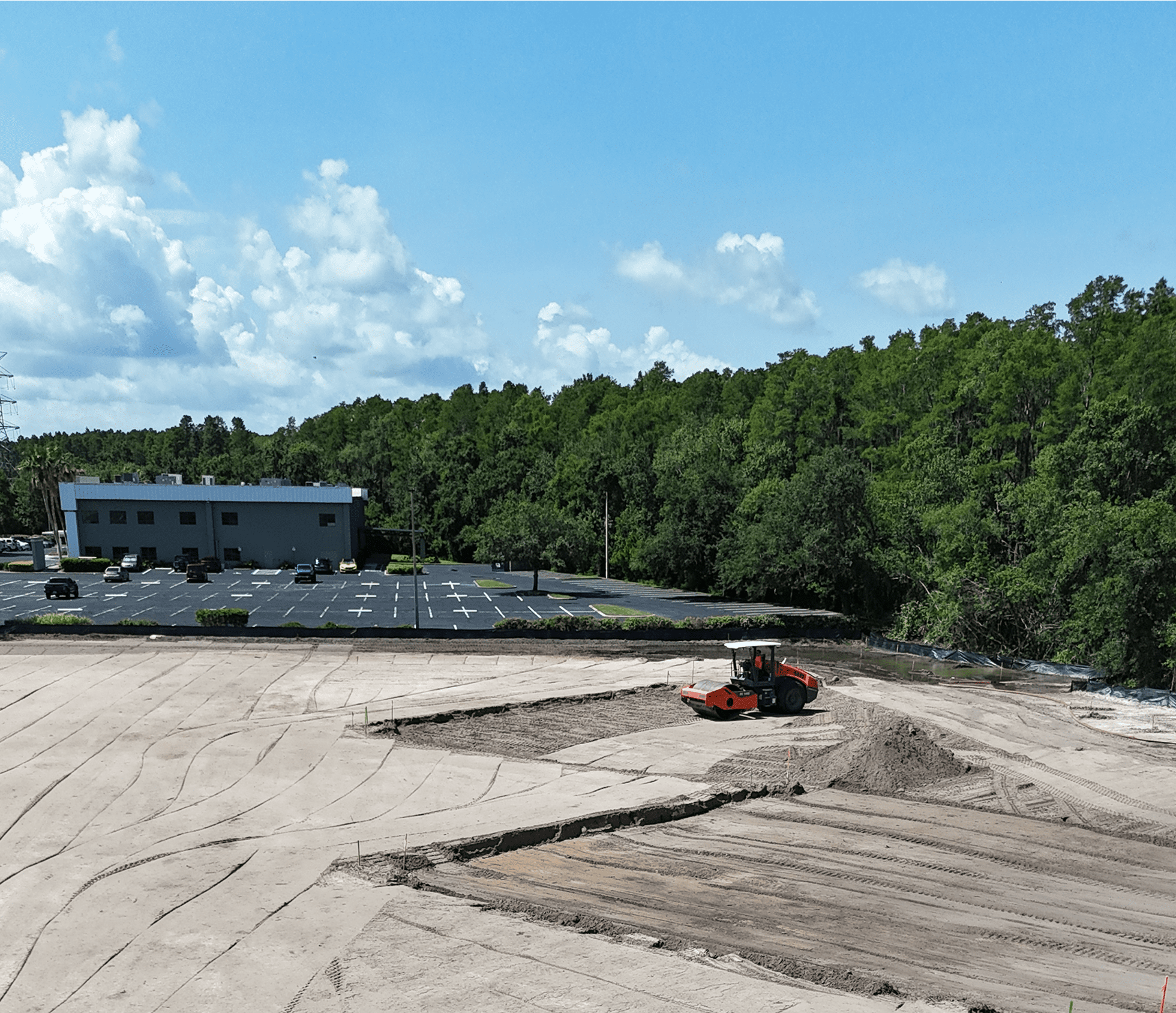 Roller compactor grading soil at construction site
