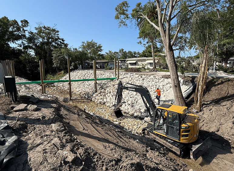 Yellow excavator working on rocky embankment